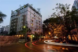 a city street with a tall white building and cars at Sabai Sathorn Service Apartment in Bangkok