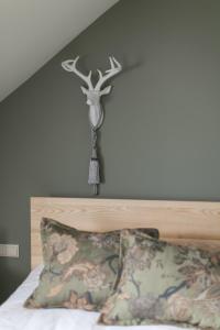 a bed with a head board with a deer head ornament on the wall at Guest House Mazais Ansis in Rubene