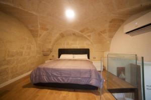 a bedroom with a bed in a stone wall at Suite del Teatro Romano in Lecce