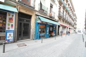 マドリードにあるApto Madrid Confort Centroの通りを歩く人々やお店が並ぶ通り