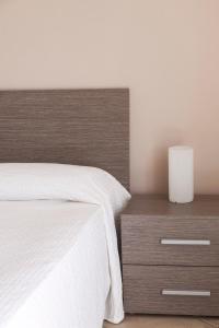 a bedroom with a white bed and a wooden nightstand at Balconies d'Orlando in Capo dʼOrlando