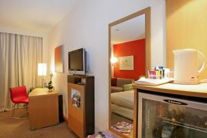 a hotel room with a fireplace and a mirror at Novotel Porto Gaia in Vila Nova de Gaia
