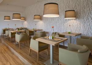 un comedor con mesas, sillas y luces en Strandhotel Bene en Burgtiefe auf Fehmarn 