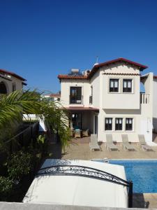 a large white house with a pool and chairs at Cy-Blue in Protaras