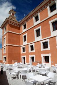 un edificio con mesas y sillas blancas delante de él en Hotel Spa Martín el Humano, en Segorbe