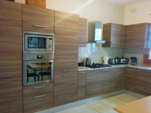 a kitchen with wooden cabinets and a table with a microwave at Mandalay in Mellieħa