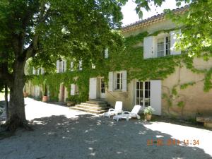 een huis met twee stoelen en een boom ervoor bij Le Côté d'Elle in Niozelles