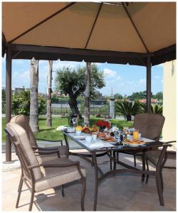 una mesa y sillas bajo una sombrilla en un patio en Hotel Visagi, en Pompeya