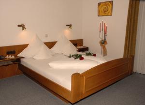 a large bed with white sheets and flowers on it at Hotel Stadtschänke in Bad König