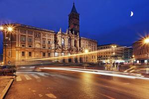 una strada di città di notte con un edificio con torre dell'orologio di Hotel Chicago a Roma