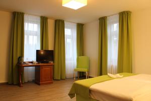 a bedroom with a bed and a desk with a television at Parkhotel Forsthaus in Tharandt