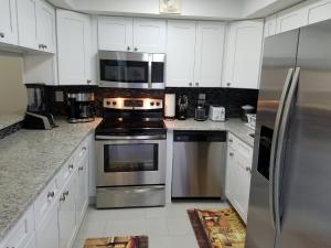 una cucina con elettrodomestici in acciaio inossidabile e armadietti bianchi di Pelican Inlet E130 a Crescent Beach