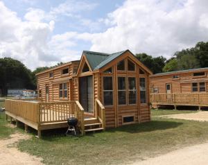 uma ampla cabina de madeira com um alpendre e um deque em Blackhawk RV Campground Loft Cabin 11 em Milton