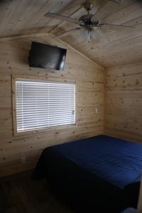 Schlafzimmer mit einem Bett, einem Deckenventilator und einem TV in der Unterkunft Pio Pico Camping Resort Cottage 1 in Jamul