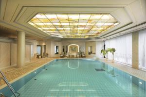 een zwembad in een gebouw met een plafond bij Maritim Hotel Ulm in Ulm