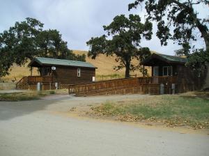 a house with a porch and a fence in front at San Benito Camping Resort One-Bedroom Cabin 9 in Paicines