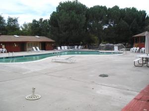 an empty swimming pool with white chairs and tables at San Benito Camping Resort One-Bedroom Cabin 9 in Paicines