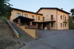 una gran casa amarilla con una escalera delante de ella en Agriturismo Il Ciabot, en Barolo