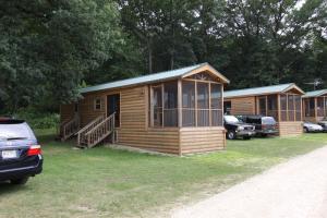 una cabaña de madera con porche y un coche aparcado delante en Blackhawk RV Campground Cabin 1 en Milton