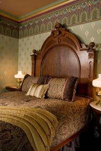 a bedroom with a large bed with a wooden headboard at The Queen Victoria in Cape May