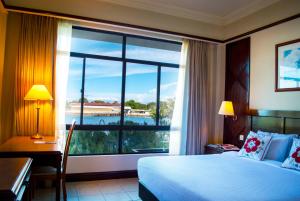a hotel room with a bed and a large window at Kudat Golf & Marina Resort in Kudat
