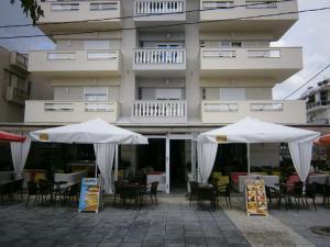 deux parapluies blancs devant un bâtiment dans l'établissement Hotel Ioanna, à Olympiakí Aktí