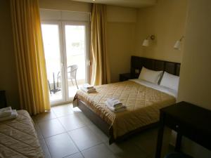 オリンピアキ・アクティにあるHotel Ioannaのベッド1台とガラスのスライドドアが備わるホテルルームです。