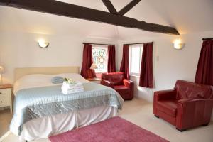 a bedroom with a bed and two red chairs at Old Selden Farm B&B in Worthing