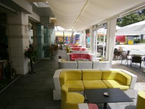 a restaurant with a yellow couch and tables and chairs at Hotel Ioanna in Olympic Beach