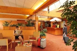 a woman sitting in a waiting room with her luggage at Logis Hôtel Le Relais du Moulin in Valençay