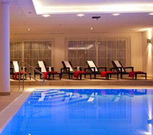 a pool in a hotel with chairs and tables at AvenidA Mountain Resort by Alpin Rentals - incl Summercard in Kaprun +198 photos