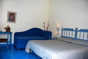a bedroom with a blue couch and a bed at Hotel La Certosa in Massa Lubrense