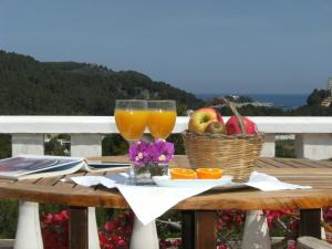 a table with a basket of fruit and two glasses of orange juice at Hotel Rural Can Maries in Puerto de San Miguel
