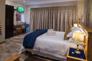 a bedroom with a large bed and a tv at Kings Halt in Bloemfontein