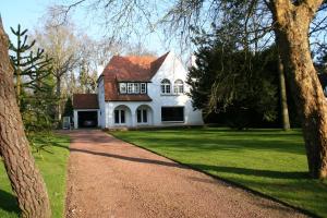 uma casa branca com um telhado vermelho e uma entrada em Belle Villa Touquettoise en fôret em Le Touquet-Paris-Plage