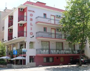 un edificio rosso e bianco con sedie sui balconi di Hotel Oblio a Rimini