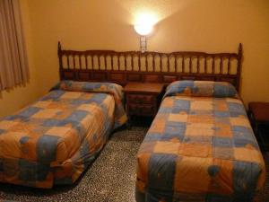 a hotel room with two beds and a lamp at Hostal Rodes in Mequinenza