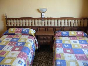 1 dormitorio con 2 camas, mesa y lámpara en Hostal Rodes en Mequinenza
