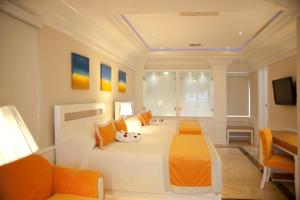 um quarto com uma grande cama branca com almofadas laranja em Cofresi Palm Beach & Spa Resort - All Inclusive em San Felipe de Puerto Plata