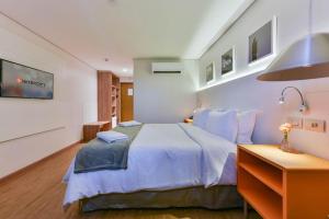 a bedroom with a large bed and a desk at Intercity Anápolis in Anápolis