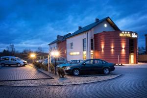 two cars parked in a parking lot in front of a building at Hotel Lord Krosno in Krosno