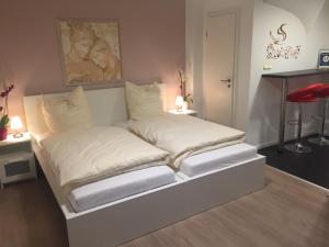 1 cama con sábanas blancas y almohadas en una habitación en Apartment Ardi, en Filderstadt