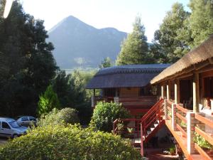een blokhut met een berg op de achtergrond bij Storms River Guest Lodge in Stormsrivier