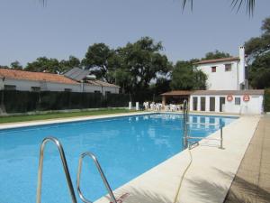 uma grande piscina azul com uma casa ao fundo em La Posada del Recovero em Genalguacil