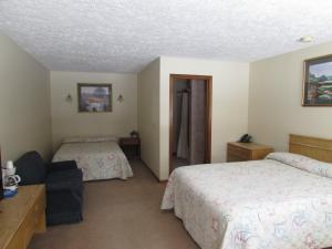 a hotel room with two beds and a chair at Woodland Motor Lodge in Grayling