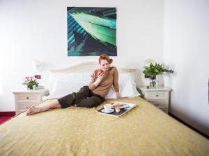 uma mulher sentada numa cama a comer comida em Locanda Ca' Lucrezia em Veneza