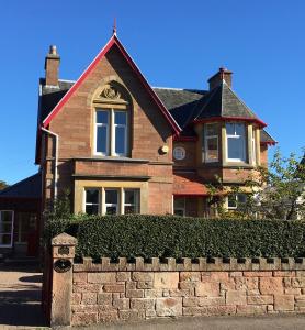 una casa de ladrillo con una valla de ladrillo delante de ella en Ronas House en Inverness