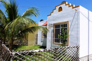a white house with a fence and palm trees at Casita Aurora in Chemuyil