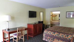 a hotel room with a bed and a desk and a bed and a desk sidx at American Inn Columbia in Columbia