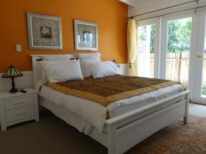 a bedroom with a large bed with orange walls at Winston Cottage in Palmwoods